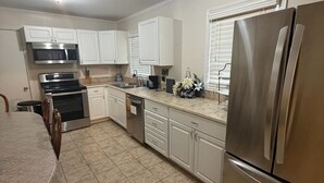A kitchen with white cabinets, stainless steel appliances, and a tiled floor. - Tranquil 3-bedroom house with AC in charming Eastman (Eastman)