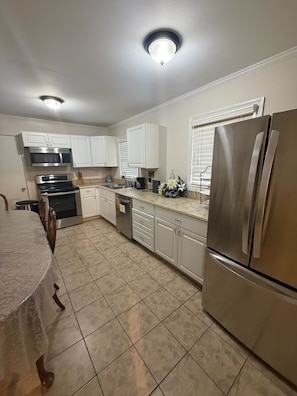 A kitchen with white cabinets, stainless steel appliances, and a tiled floor.