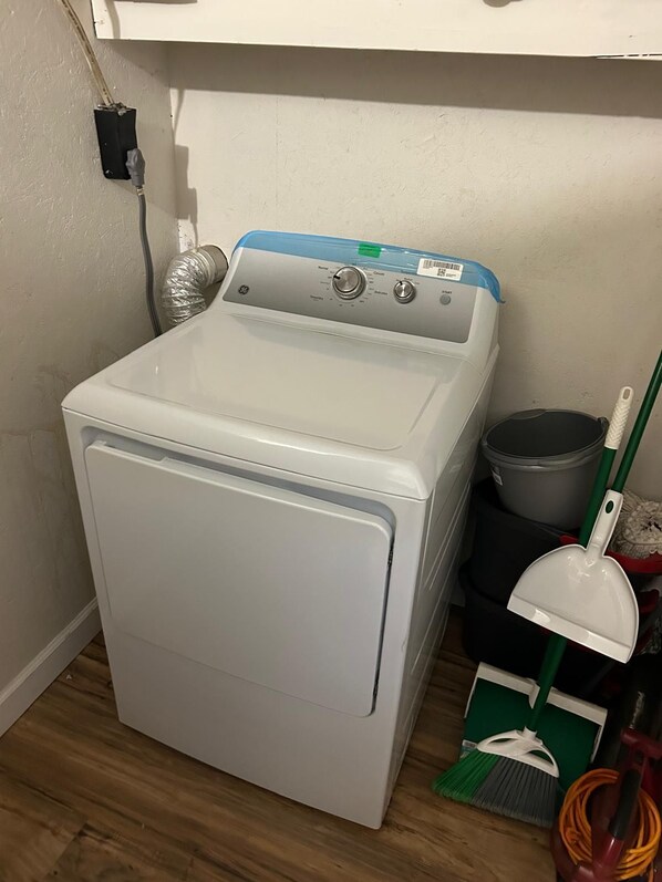 Una lavadora de carga frontal blanca con panel de control, una manguera y una ventilación.