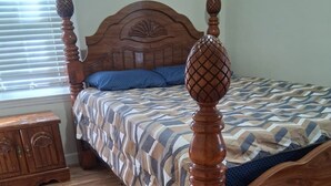 A wooden four-poster bed with a geometric patterned bedspread, a small wooden nightstand, and a window with blinds. - Tranquil 3-bedroom house with AC in charming Eastman (Eastman)
