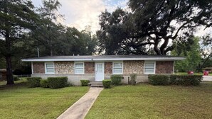A single-story house with a front yard, a pathway leading to the front door, and a large tree to the right. - Tranquil 3-bedroom house with AC in charming Eastman (Eastman)