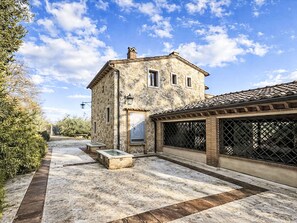 A stone building with a tiled roof, a wooden bench, and a metal gate. - Le More by Interhome (Penna in Teverina)