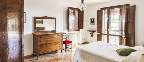 A bedroom with a bed, dresser, chair, and a window with a view.
