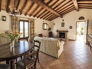 A dining area with a wooden table and chairs, a sofa, a fireplace, and a view of the outdoors. - Le More by Interhome (Penna in Teverina)
