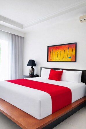 Una habitació d'hotel amb un llit gran, una tauleta de nit amb una làmpada, un quadre a la paret i una finestra amb cortines.