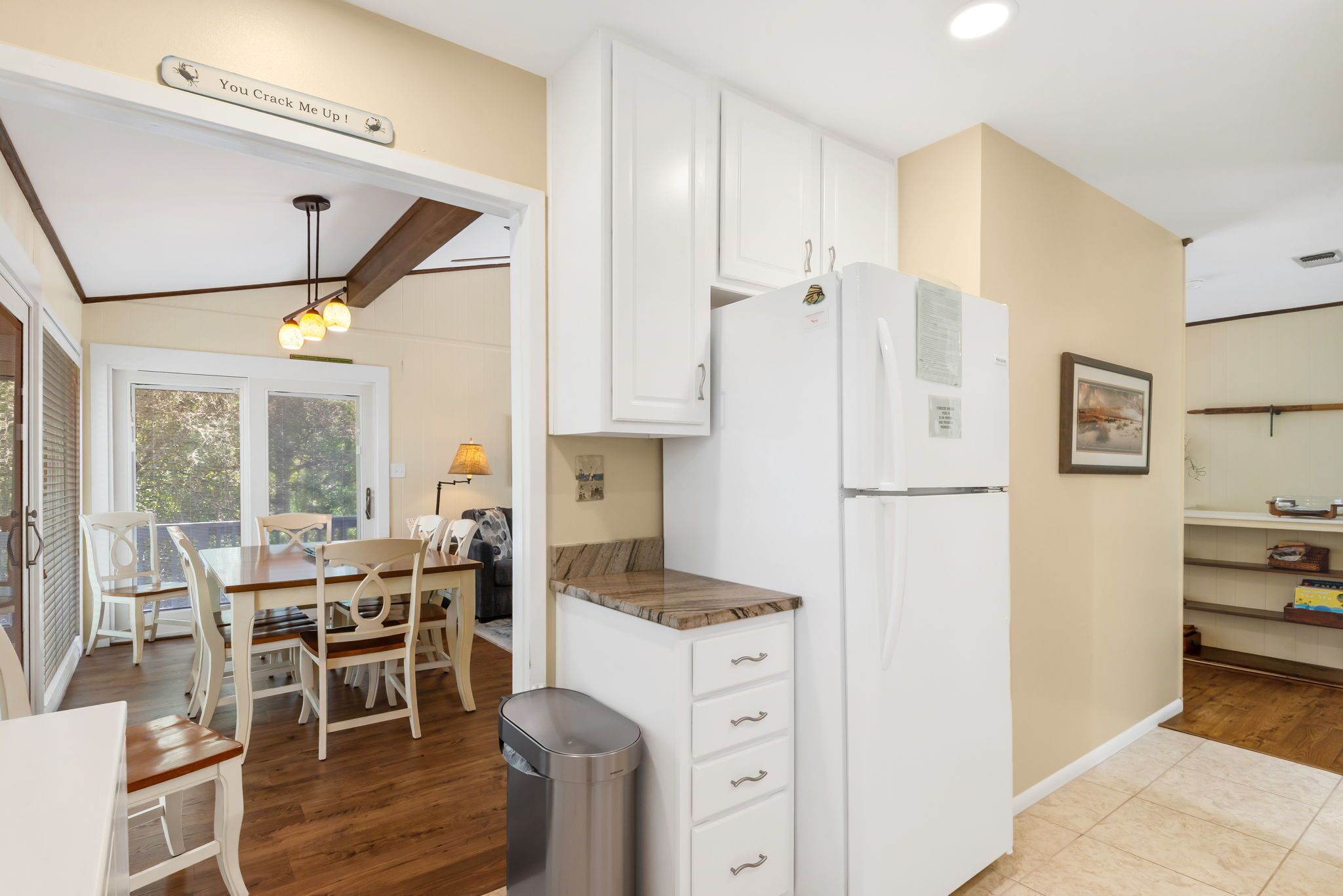 A kitchen with white cabinets, a wooden countertop, and a stainless steel trash can.