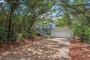 A residential property with a driveway leading to a garage, surrounded by trees and vegetation. - Pet Friendly 3BR Home in Miramar Beach w Private Beach Access (Miramar Beach)
