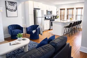 A modern kitchen with white cabinets, a stainless steel refrigerator, and a microwave. - 9 BR Movie Theater Duplex Near Cleveland Clinic! (Cleveland)