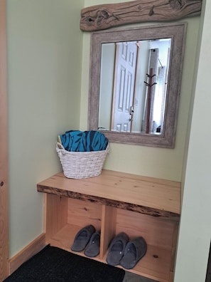 Un banco de madera con una cesta tejida y un par de zapatillas.