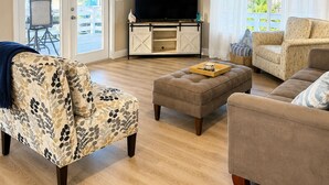 Una sala de estar con ventilador de techo, televisor y sofá.