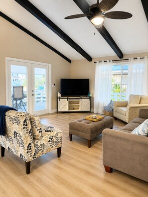 A living room with a ceiling fan, a TV, and a sofa.