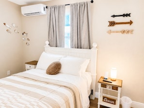 A bedroom with a bed, a nightstand, a lamp, and wall decorations including fish and arrows. - Huge water front 3-bedroom house with boat dock and pool (Hudson)
