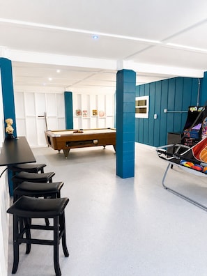 A pool table with a blue wall and a hanging chair in a room with white walls and a ceiling light. - Huge water front 3-bedroom house with boat dock and pool (Hudson)