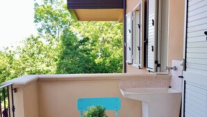 Ein Balkon mit Tisch, Stühlen, einem Blumentopf und einem Fenster mit Rollläden.