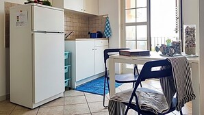 Eine kleine Küche mit Kühlschrank, Schränken und einem Fenster mit Blick.