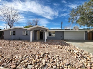A two-story house with a garage, a covered entryway, and a driveway with a rock bed.
