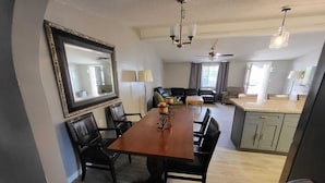 A dining area with a wooden table, black chairs, a large mirror, and a ceiling fan.
