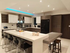 Una cocina moderna con una isla central, taburetes de bar y un horno empotrado.