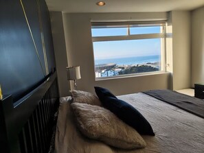 Un dormitorio con un ventanal grande, una cama, un televisor y un radiador.