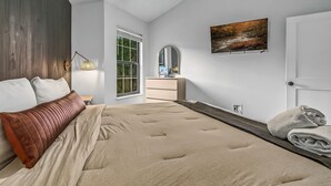 Una camera da letto con un letto, una cassettiera, uno specchio, una finestra e un quadro appeso al muro.