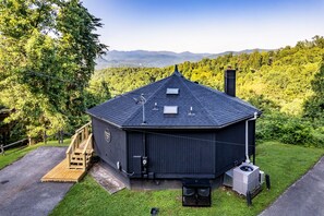 Eine schwarze Holzhütte mit geneigtem Dach, Schornstein und einer kleinen Veranda mit einer Holztreppe.