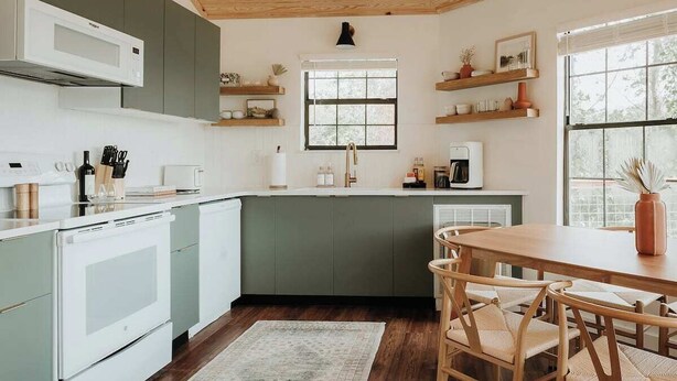 Cucina con forno a microonde, forno e tavolo da pranzo in legno con sedie.