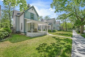 A two-story house with a covered porch and a well-maintained lawn. - Canvas & Coast DT TC, Games + Fire Pit | Pets Ok (Traverse City)