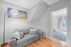 A modern living room with a grey sofa, a floor lamp, and a painting on the wall. - Canvas & Coast DT TC, Games + Fire Pit | Pets Ok (Traverse City)