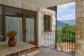Ein Balkon mit einer Steinsäule, einem Holztisch und einem Blumentopf.