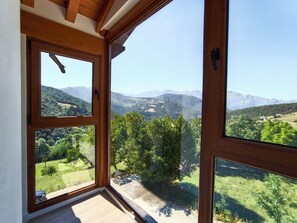 Ein Zimmer mit großen Fenstern und Blick auf eine gebirgige Landschaft.