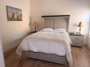 Une chambre à coucher avec un lit, des tables de chevet, des lampes et un tableau au mur.
