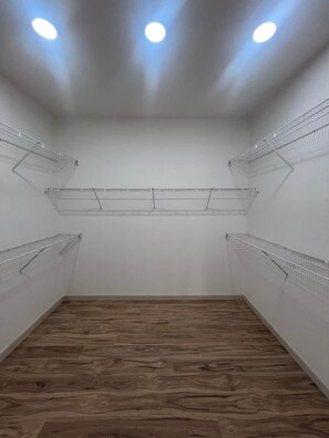 A room with a wooden floor, white walls, and metal shelving units. - Allegro Way (Albuquerque)