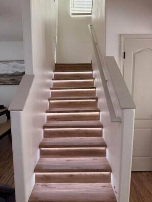 A wooden staircase with white handrails and a white door at the top. - Allegro Way (Albuquerque)