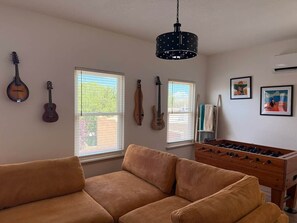 Ein Zimmer mit einer Couch, einem Kicker und an der Wand befestigten Musikinstrumenten.