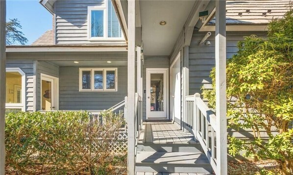 A two-story house with a covered porch, a visible door, and a small garden area. - 6BR w/ Pool near Wintergreen & Wineries, Sleeps 19 (Nellysford)