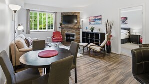Ein modernes Wohnzimmer mit Kamin, einem runden Esstisch und einer Couch.