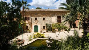 A stone building with a courtyard, a fountain, and a green door.