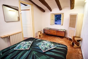 A bedroom with a bed, a dresser, a mirror, a window, and a radiator.