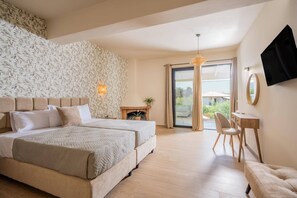 Ein Schlafzimmer mit einem großen Bett, einem Schreibtisch, einem Sessel, einem Kamin und Blick durch eine Glastür.