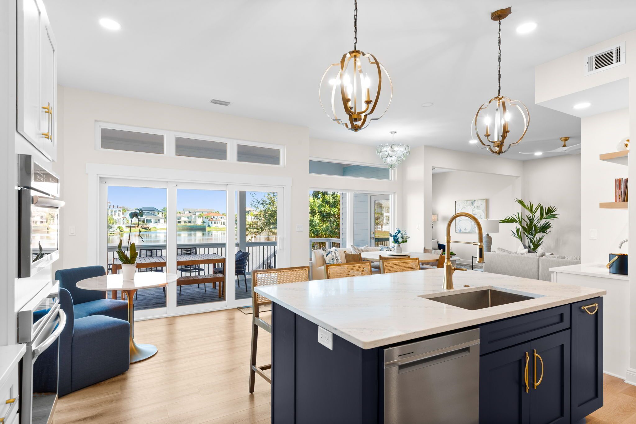 A modern kitchen with a large island, pendant lighting, and a view to the outside.