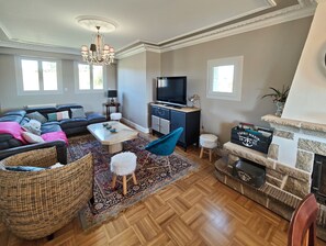 A living room with a sectional sofa, a coffee table, a TV, a fireplace, and a stone fireplace surround. - Castel Ar Vugale - Family home with sea view (Plouénan)
