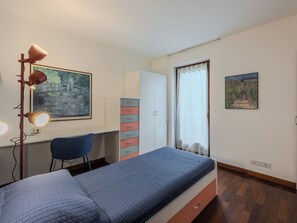 Ein Schlafzimmer mit Bett, Schreibtisch, Stuhl, Kleiderschrank und zwei Bildern.