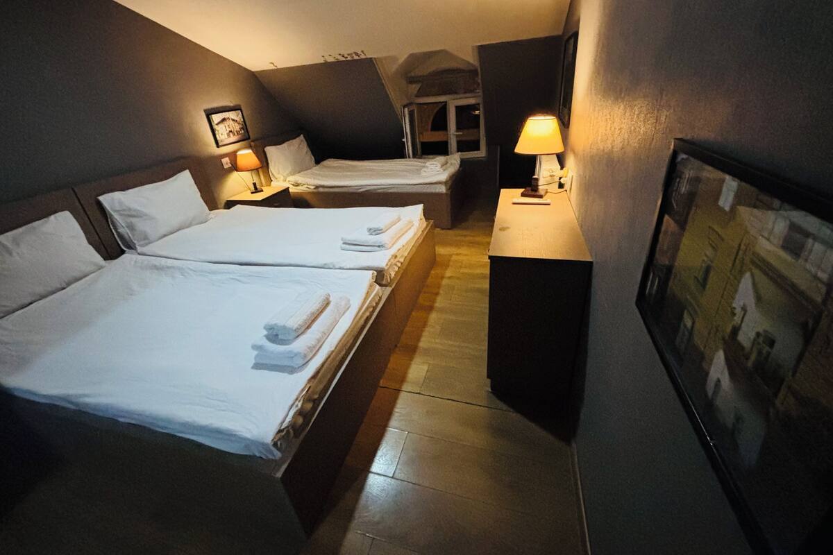 A hotel room with two beds, a small desk, a lamp, and a framed picture on the wall.