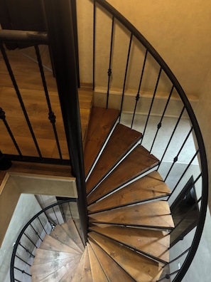 A spiral staircase with wooden steps and black metal railings. - city guli hotel (Tbilisi)