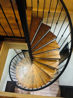 A spiral staircase with wooden steps and black metal railings. - city guli hotel (Tbilisi)