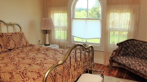 Une chambre à coucher avec un lit, une chaise, une lampe et une fenêtre donnant sur un beau paysage.