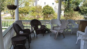 A covered porch with wicker chairs and a white railing. - Experience Luxury Historic Home Near Beach and Astoria (Warrenton)