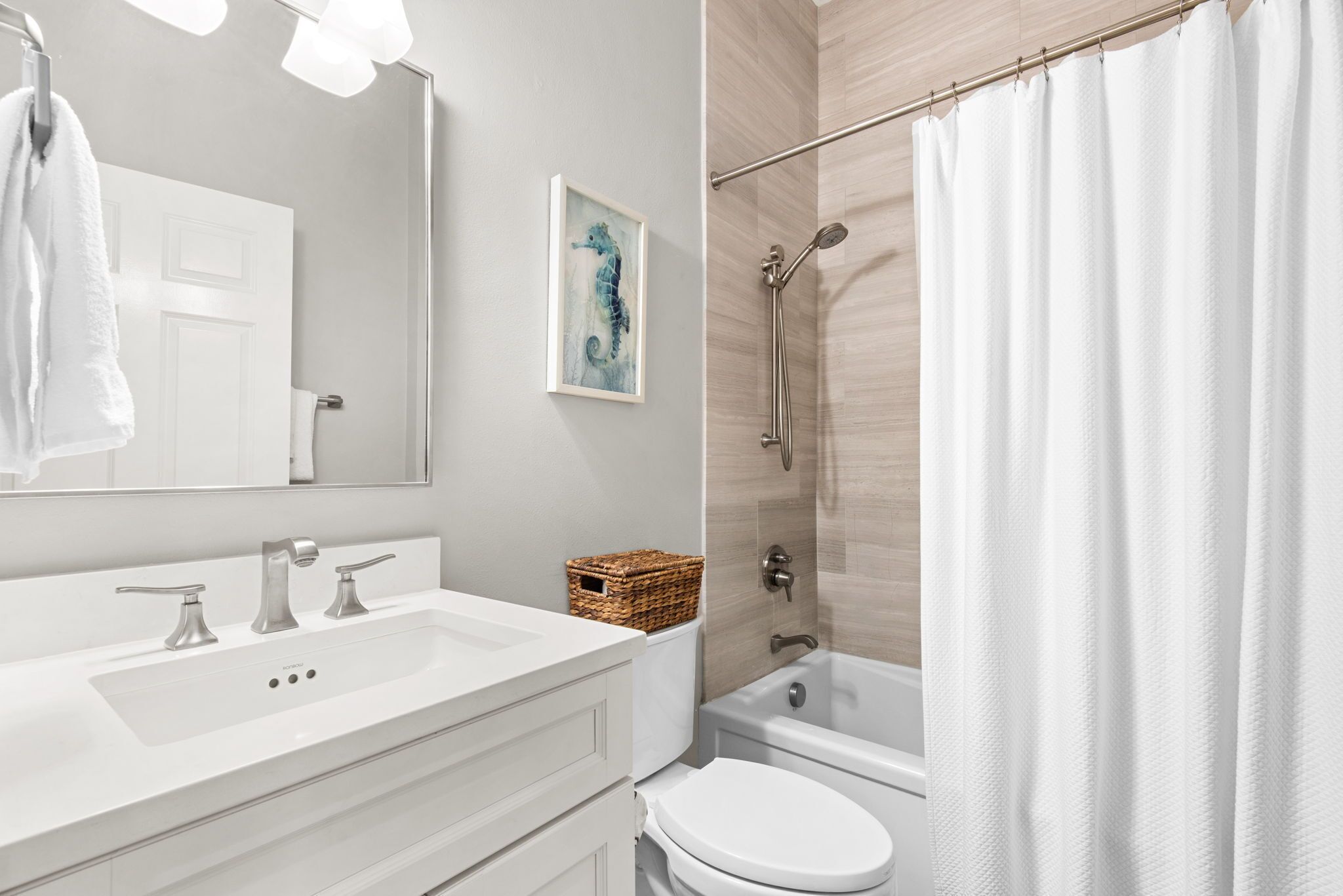 A bathroom with a white sink, mirror, and toilet.