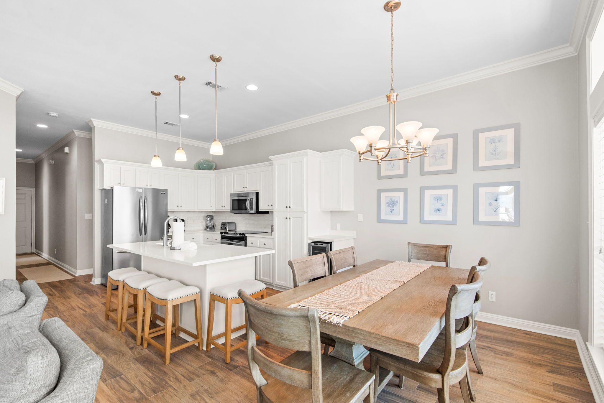 A modern kitchen with white cabinets, stainless steel appliances, and a wooden dining table.