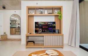 Uma sala de estar moderna com um móvel de entretenimento de madeira, uma TV de tela plana e um espaço de estar aconchegante.